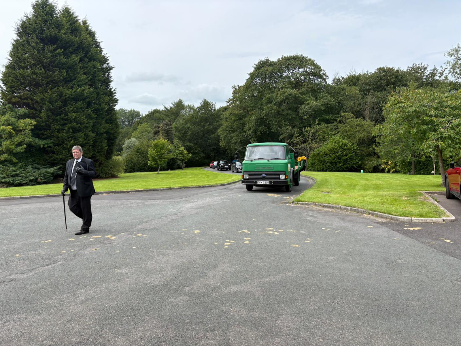 A funeral director walking ahead of the carriage on its approach